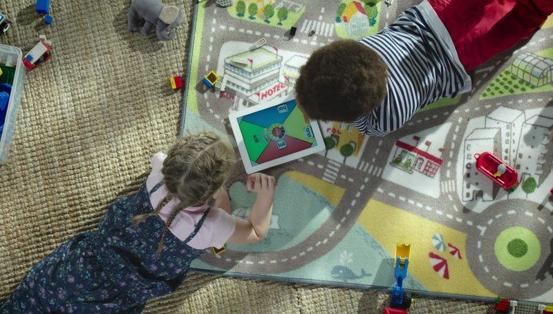 Two children play on a road-map rug, shot from above